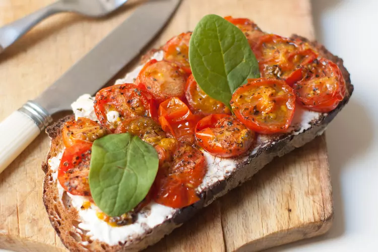 une tartine de tomates cerise rôties avec 2 feuilles de basilic dessus