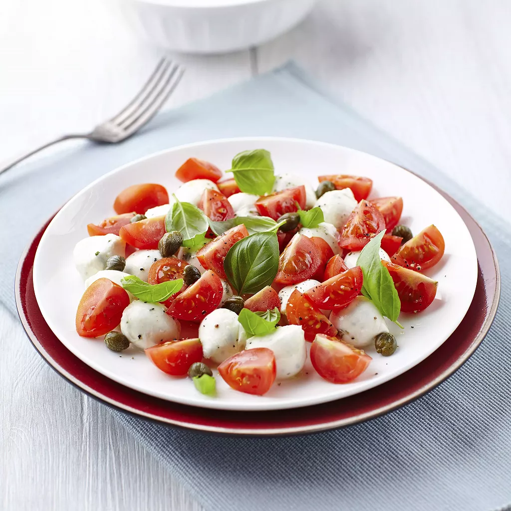 assiette avec des tomates cerises, basilic et mozzarella